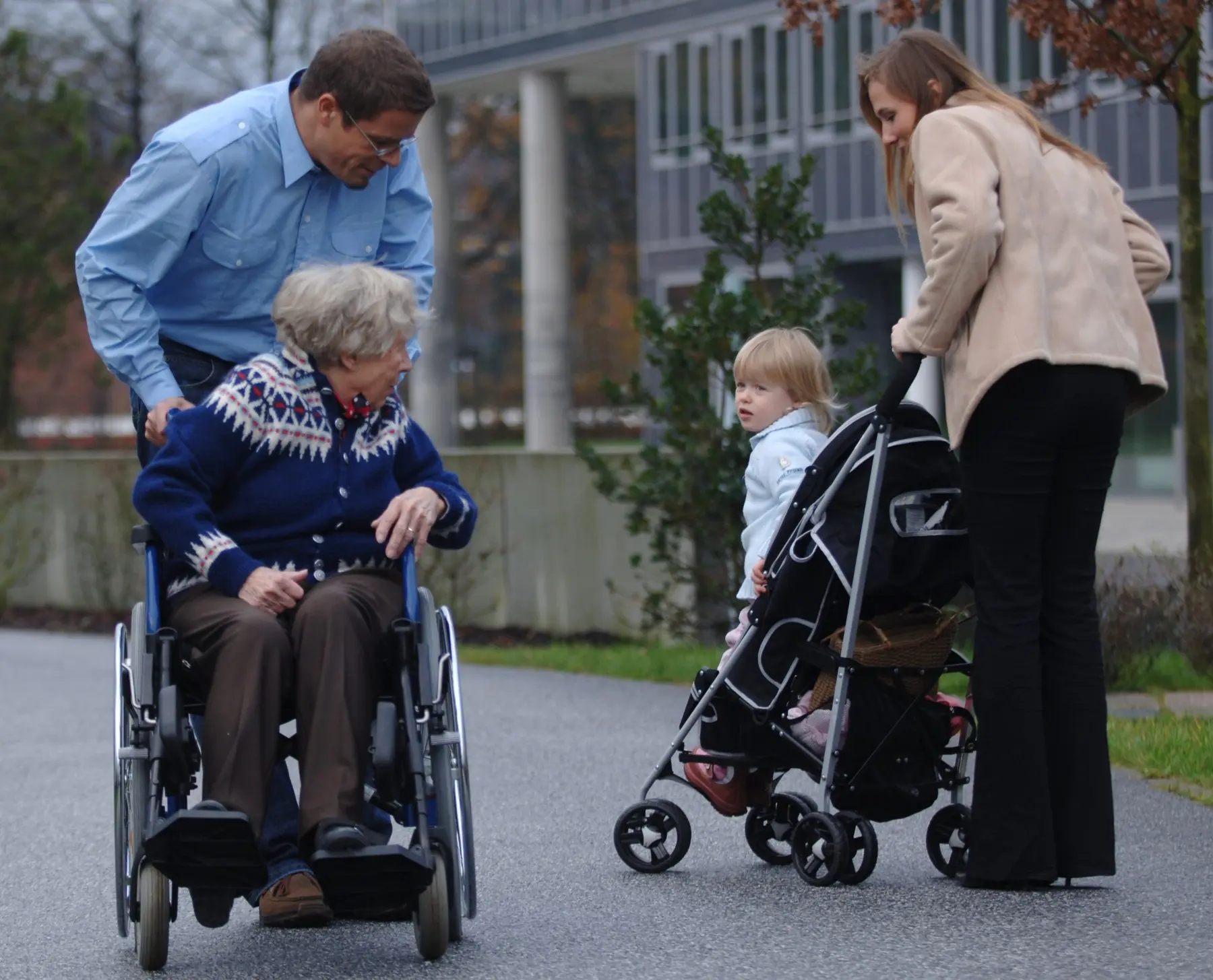 Begegnung zwischen einer älteren Dame, einer Familie und einem Mitarbeiter im Freien